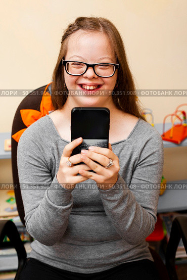 smiley girl with down syndrome holding phone. Стоковое фото, агентство Ingram Publishing / Фотобанк Лори