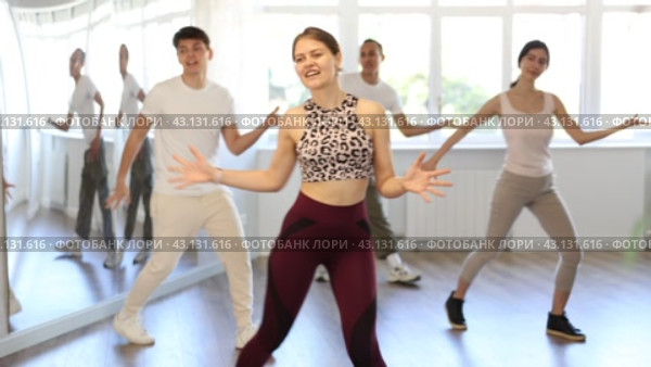 Smiling active young girl enjoying contemporary vigorous dance at group class in light mirrored studio. Стоковое видео, видеограф Яков Филимонов / Фотобанк Лори