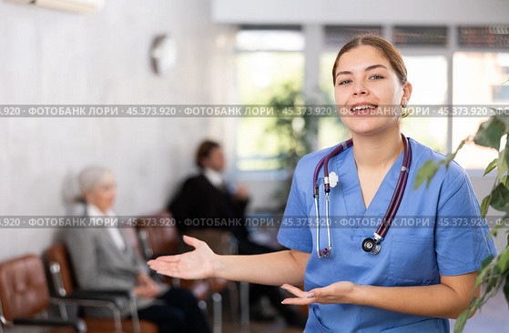 smiling female medical receptionist affably waiting for patients of clinic in waiting room. Стоковое фото, фотограф Яков Филимонов / Фотобанк Лори