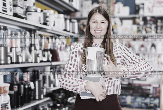 Smiling girl seller showing liquidiser in shop. Стоковое фото, фотограф Яков Филимонов / Фотобанк Лори