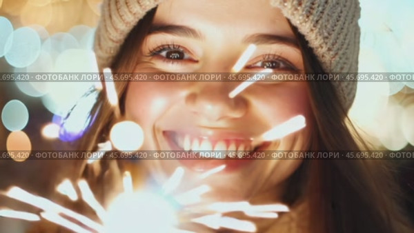Smiling Girl with Fire Sparkler Glow in the Winter Season. pleased happy smiling young 20s woman is holding a bright sparkler in a festive winter setting. Glowing blur bokeh light on background. Стоковое AI-видео, аниматор Марина Демидюк / Фотобанк Лори