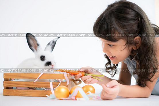 Smiling little girl and with their beloved fluffy rabbit, showcasing the beauty of friendship between humans and animals. Стоковое фото, агентство Ingram Publishing / Фотобанк Лори