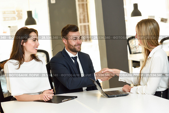 Smiling young couple shaking hands with an insurance agent or investment adviser. Three people meeting in an office reaching an agreement. Стоковое фото, фотограф Javier Sánchez Mingorance / Ingram Publishing / Фотобанк Лори