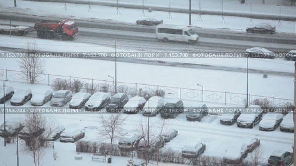 Снегопад в городе, вид на стоянку и автодорогу с машинами, спальный микрорайон Санкт-Петербурга. Стоковое видео, видеограф Кекяляйнен Андрей / Фотобанк Лори
