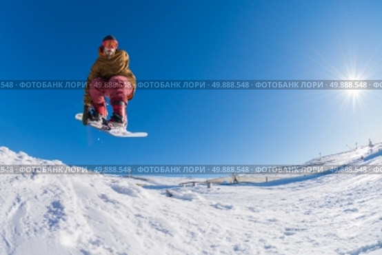 Snowboarder executing a radical jump against blue sky. Стоковое фото, агентство Ingram Publishing / Фотобанк Лори