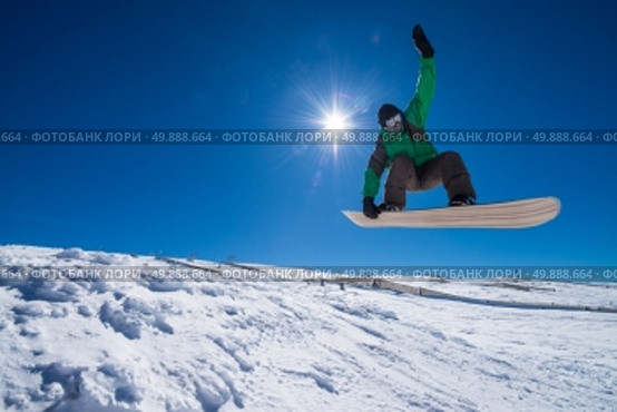 Snowboarder executing a radical jump against blue sky. Стоковое фото, агентство Ingram Publishing / Фотобанк Лори
