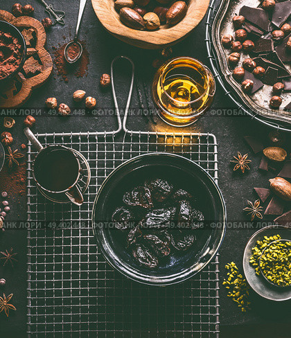 Soaked in rum prunes for homemade pralines with various chocolate, spices and nuts ingredients on dark table background with vintage kitchen utensils, top view. Confectioner or patisserie concept. Стоковое фото, агентство Ingram Publishing / Фотобанк Лори