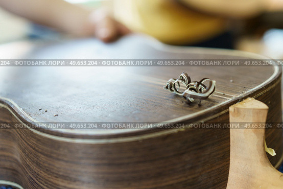 Soft focus of unrecognizable craftsman carving part for Spanish flamenco guitar on workbench during work in luthier workshop. Unrecognizable Spanish flamenco guitar luthier crafting guitar part. Стоковое фото, агентство Ingram Publishing / Фотобанк Лори