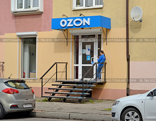Сотрудница пункта по выдаче заказов онлайн-магазина OZON стоит около входной двери (2021 год). Редакционное фото, фотограф Ирина Борсученко / Фотобанк Лори
