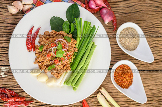 Spicy Minced Pork Salad on a white plate with red onion, lemon grass, garlic, yardlong beans, kaffir lime leaves, and spring onion. Стоковое фото, агентство Ingram Publishing / Фотобанк Лори