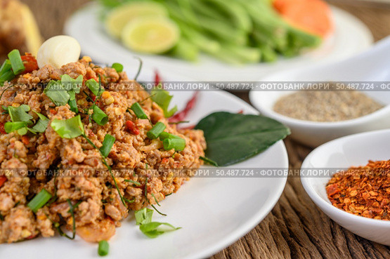 Spicy Minced Pork Salad on a white plate with red onion, lemon grass, garlic, yardlong beans, kaffir lime leaves, and spring onion. Стоковое фото, агентство Ingram Publishing / Фотобанк Лори