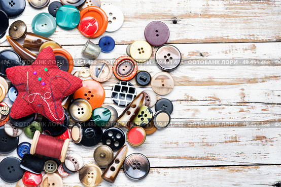 Spools of threads and buttons on wooden table. Buttons and threads with needle. Стоковое фото, агентство Ingram Publishing / Фотобанк Лори