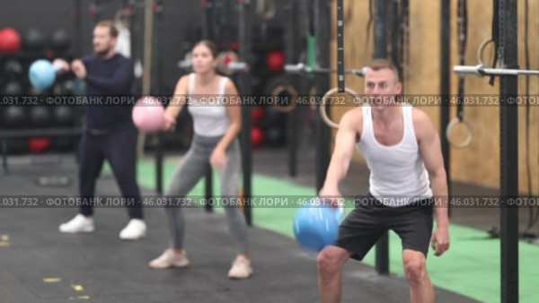 Sporty young adult man exercising with kettlebell to strengthen body muscles in modern gym during group workout. Physical activity and bodybuilding concept. Стоковое видео, видеограф Яков Филимонов / Фотобанк Лори