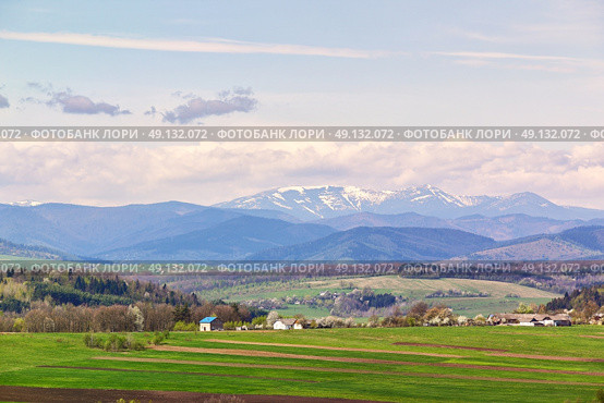 Spring fields and orchard blossom on foothills. Sunny green spring landscape. Spring fields and blooming trees. Village and town behind foothills. Стоковое фото, агентство Ingram Publishing / Фотобанк Лори