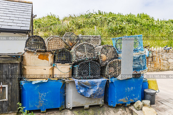 Stacked lobster pots, crab traps and blue fish crates at a coastal fishing yard. Стоковое фото, фотограф Zydrius Tartenis / Фотобанк Лори
