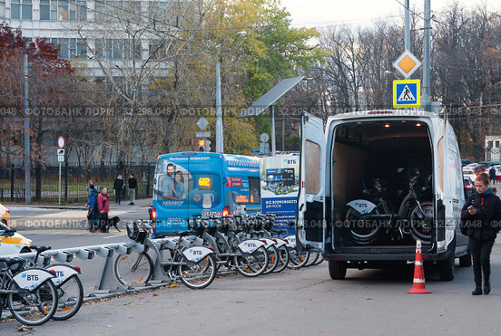 Станция проката велосипедов на Ботанической улице в Москве. Рядом стоит микроавтобус техобслуживания велопроката с распахнутыми задними дверями. В кузове видны велосипеды с маркировкой "ВТБ" (2019 год). Редакционное фото, фотограф Наталья Николаева / Фотобанк Лори