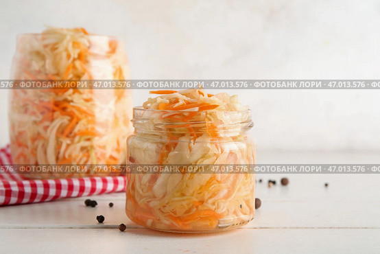 Стеклянная банка с вкусной квашеной капустой и рассыпанными горошинами перца на столе на белом фоне. Крупный план. Стоковое фото, фотограф Pixel_shot / Фотобанк Лори