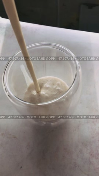 Струйка густого молочно-бананового смузи стекает в прозрачный стакан. Съемка в замедленном режиме. Стоковое видео, видеограф Ярославский Максим / Фотобанк Лори