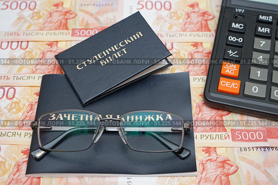 Студенческий билет, зачетная книжка, очки и калькулятор лежат на российских денежных купюрах. Стоковое фото, фотограф Цибаев Алексей / Фотобанк Лори