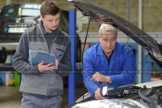 student with instructor repairing a car during apprenticeship. Стоковое фото, агентство Ingram Publishing / Фотобанк Лори