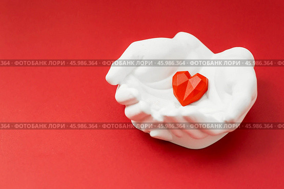 Stylish banner. In his hands, a red heart on a red background is made of plaster. World Health, Love and Insurance Day. World Heart, Health and Organ Donor Day. Стоковое фото, фотограф Photojuli / Фотобанк Лори