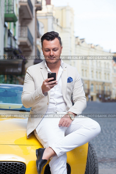 Stylish man using smartphone near sport car. Стоковое фото, агентство Ingram Publishing / Фотобанк Лори