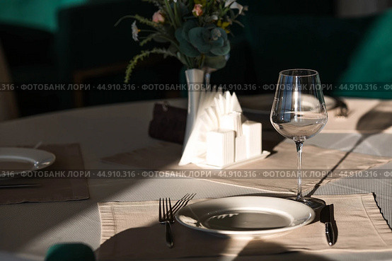 Stylish table setting. Glass glasses, plates, cutlery on the table. Wedding service, reception at the dining table. A birthday, a baptism, a festive event. Стоковое фото, фотограф Photojuli / Фотобанк Лори