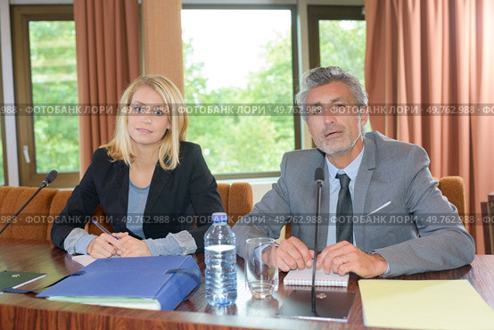 Suited man and woman sat behind desk. Стоковое фото, агентство Ingram Publishing / Фотобанк Лори