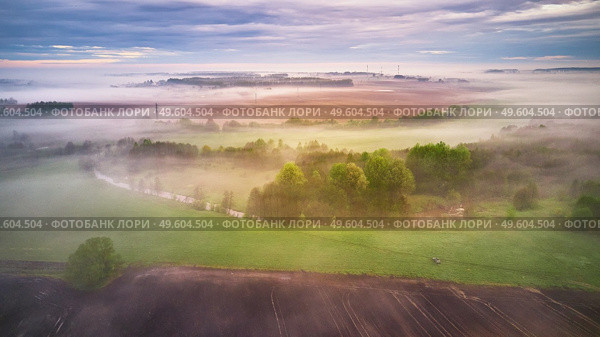 Summer cloudy rainy foggy morning panorama. Rural misty river, fields, meadow, village. Spring overcast moody weather. Blooming trees and bushes. Belarus, Minsk region. Стоковое фото, агентство Ingram Publishing / Фотобанк Лори