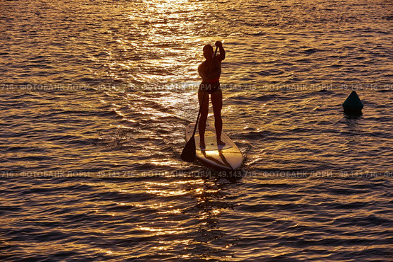 SUP Stand up Surf girl with paddle at sunset. Стоковое фото, агентство Ingram Publishing / Фотобанк Лори