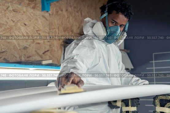 Surfboard manufacturing, Shaper working on board details. Concept of industrial manufacturing, qualified professional, occupation and employment. Стоковое фото, агентство Ingram Publishing / Фотобанк Лори