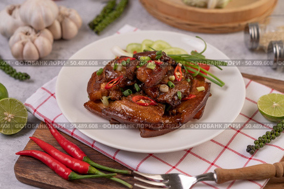 Sweet pork on a white plate with chopped scallions, chili, lime, cucumber, tomato, and garlic. Стоковое фото, агентство Ingram Publishing / Фотобанк Лори