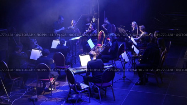Symphony orchestra concert in mysterious darkness under stage spotlights. The conductor controls the orchestra. Редакционное видео, видеограф Евгений Ткачёв / Фотобанк Лори