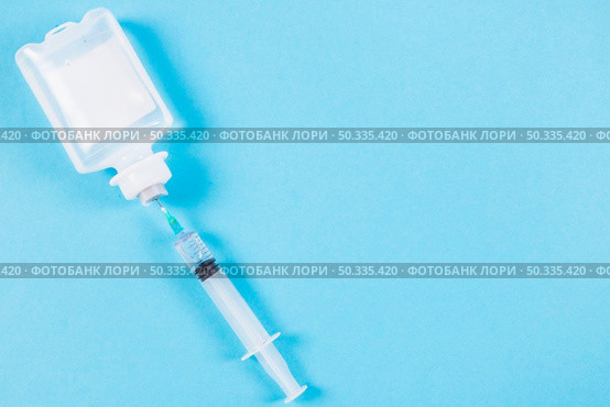 syringe inserted normal saline solution plastic bottle blue background. Стоковое фото, агентство Ingram Publishing / Фотобанк Лори