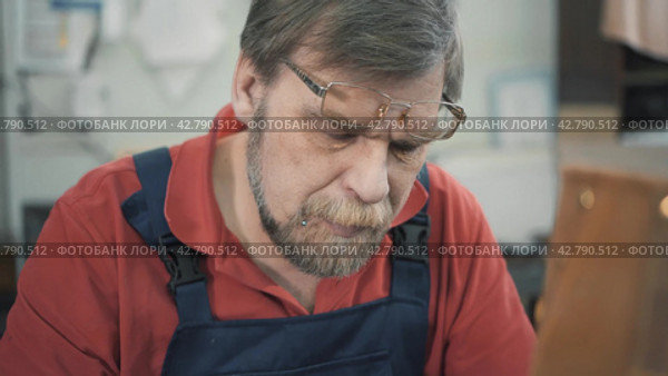 Tailor in a sewing workshop sews with a needle and thread. Portrait  close-up. Стоковое видео, видеограф EStarodubov / Фотобанк Лори