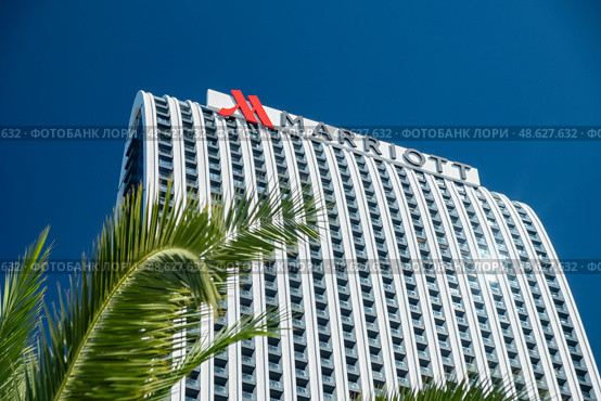 Tall hotel building Marriott under a clear blue sky surrounded by palm trees in a vibrant urban setting.Batumi, Georgia - October 10, 2024. Редакционное фото, фотограф Климов Денис / Фотобанк Лори