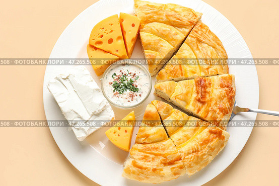 Тарелка с кусочками вкусного сырного пирога и ингредиентами на бежевом фоне. Стоковое фото, фотограф Pixel_shot / Фотобанк Лори