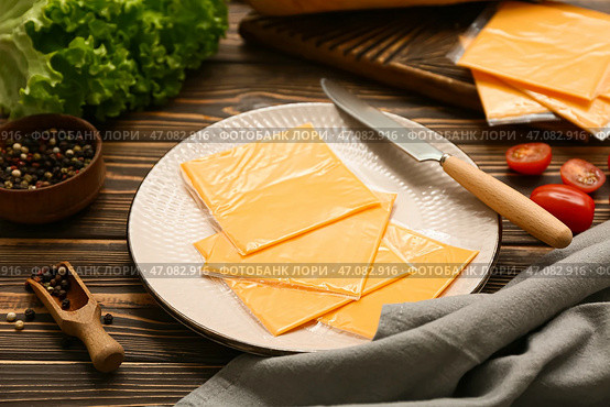 Тарелка с ломтиками вкусного плавленого сыра, перцем горошком и свежими овощами на деревянном столе. Стоковое фото, фотограф Pixel_shot / Фотобанк Лори