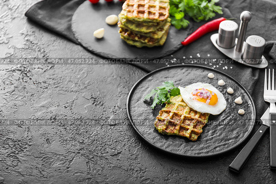 Тарелка с вкусной кабачковой вафлей и жареным яйцом на темном столе. Стоковое фото, фотограф Pixel_shot / Фотобанк Лори