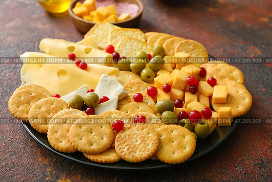 Тарелка с вкусными крекерами с сыром и закусками на фоне гранж. Стоковое фото, фотограф Pixel_shot / Фотобанк Лори