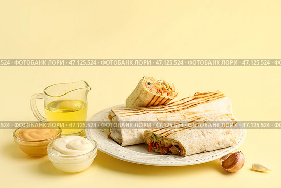 Тарелка вкусного шаурмы со соусами и маслом на бежевом фоне. Стоковое фото, фотограф Pixel_shot / Фотобанк Лори
