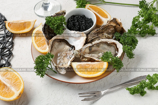 Тарелка вкусных устриц с лимоном и черной икрой на белом фоне. Стоковое фото, фотограф Pixel_shot / Фотобанк Лори