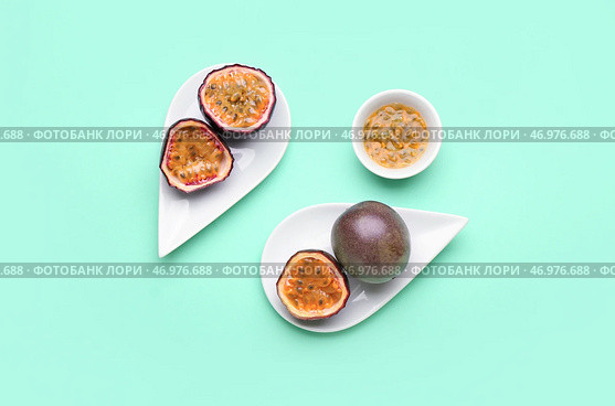 Тарелки с вкусными маракуйями и миска с мякотью на зеленом фоне. Стоковое фото, фотограф Pixel_shot / Фотобанк Лори