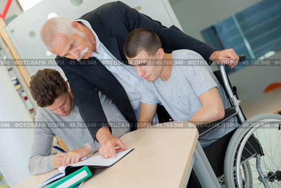 teacher helping a disable student at class. Стоковое фото, агентство Ingram Publishing / Фотобанк Лори