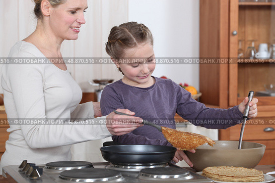 Teaching her daughter to make crepes. Стоковое фото, агентство Ingram Publishing / Фотобанк Лори