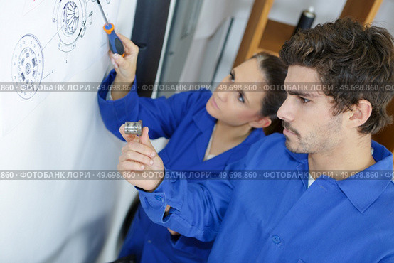 Technicians identifying part on exploded technical drawing. Стоковое фото, агентство Ingram Publishing / Фотобанк Лори