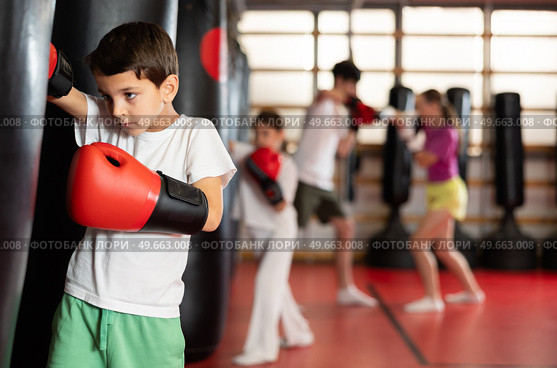 Teen boy in boxing gloves hits punching bag in gym. Стоковое фото, фотограф Яков Филимонов / Фотобанк Лори