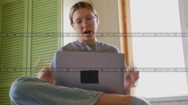 Teen girl school student wear headphones watching online webinar, talking through webcam looking at laptop. Teenager conducting video conference on computer at home, chatting online with friends. 4K. Стоковое видео, видеограф Марина Демидюк / Фотобанк Лори