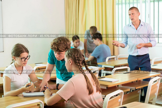 Teen girls and boys solving teacher assignments in small groups. Стоковое фото, фотограф Яков Филимонов / Фотобанк Лори