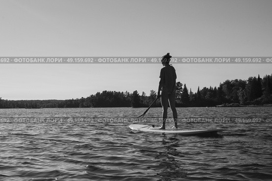 Teenage girl paddleboarding in the lake, Lake of The Woods, Ontario, Canada. Стоковое фото, агентство Ingram Publishing / Фотобанк Лори